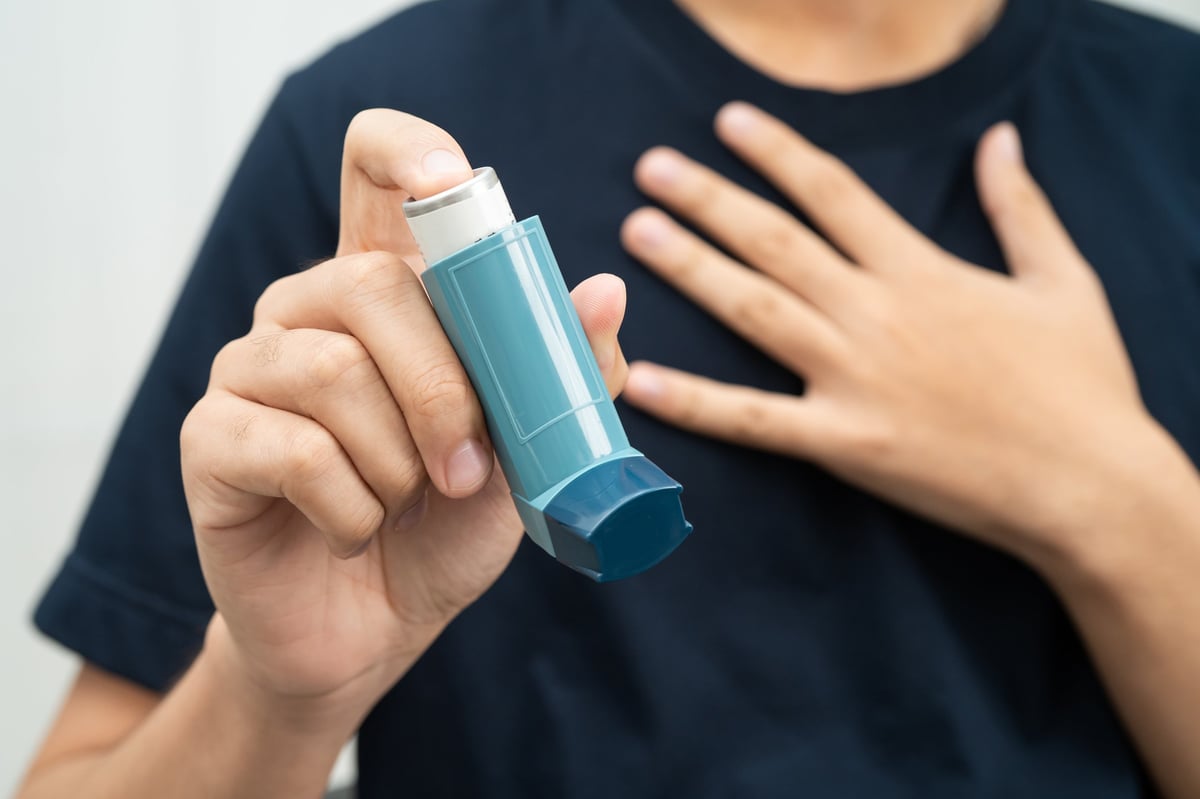 Asthma and chronic obstructive pulmonary disease COPD, Asian young man using metered dose inhaler MDI.